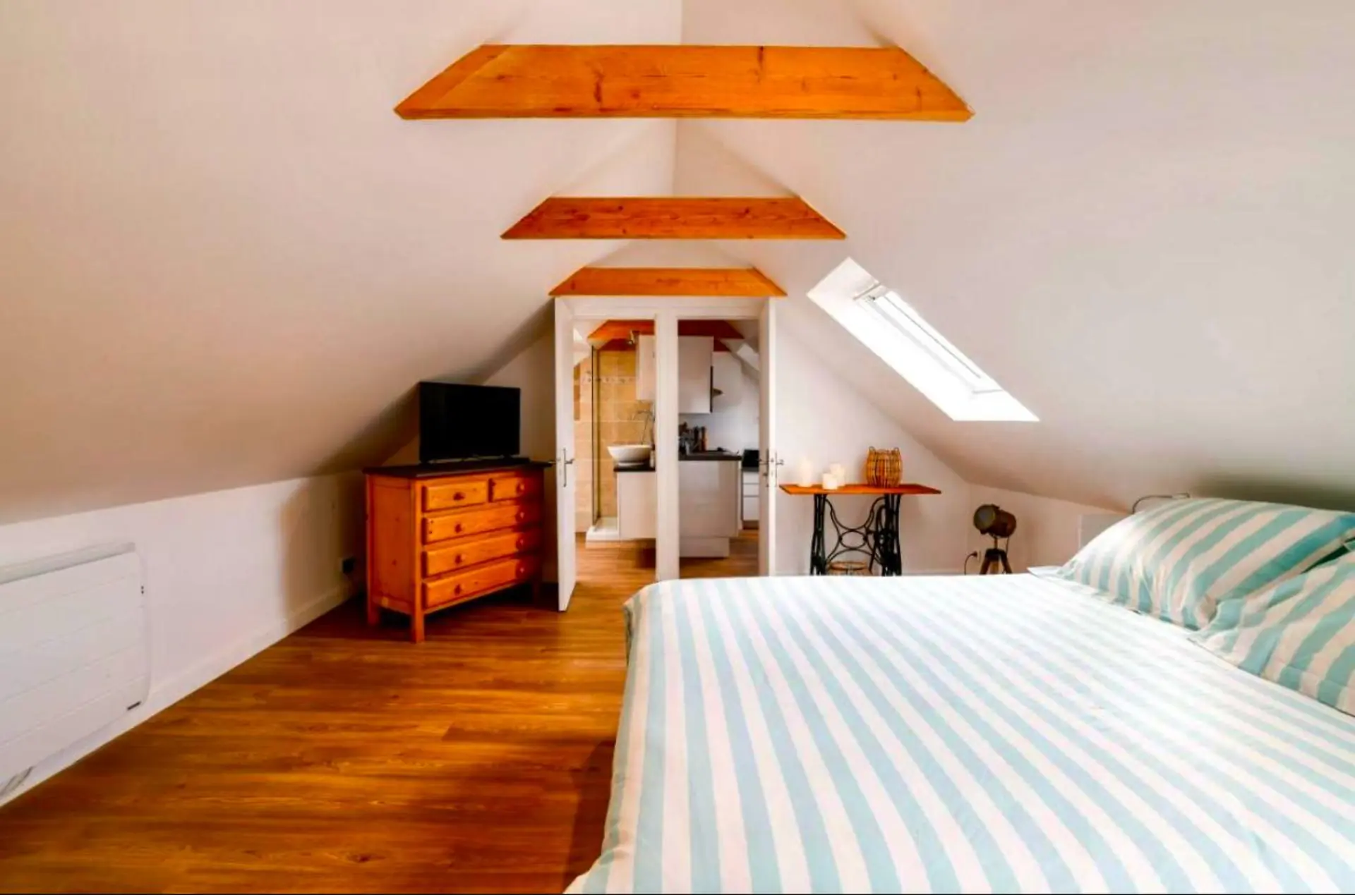 Chambre mansardée avec commode et télévision