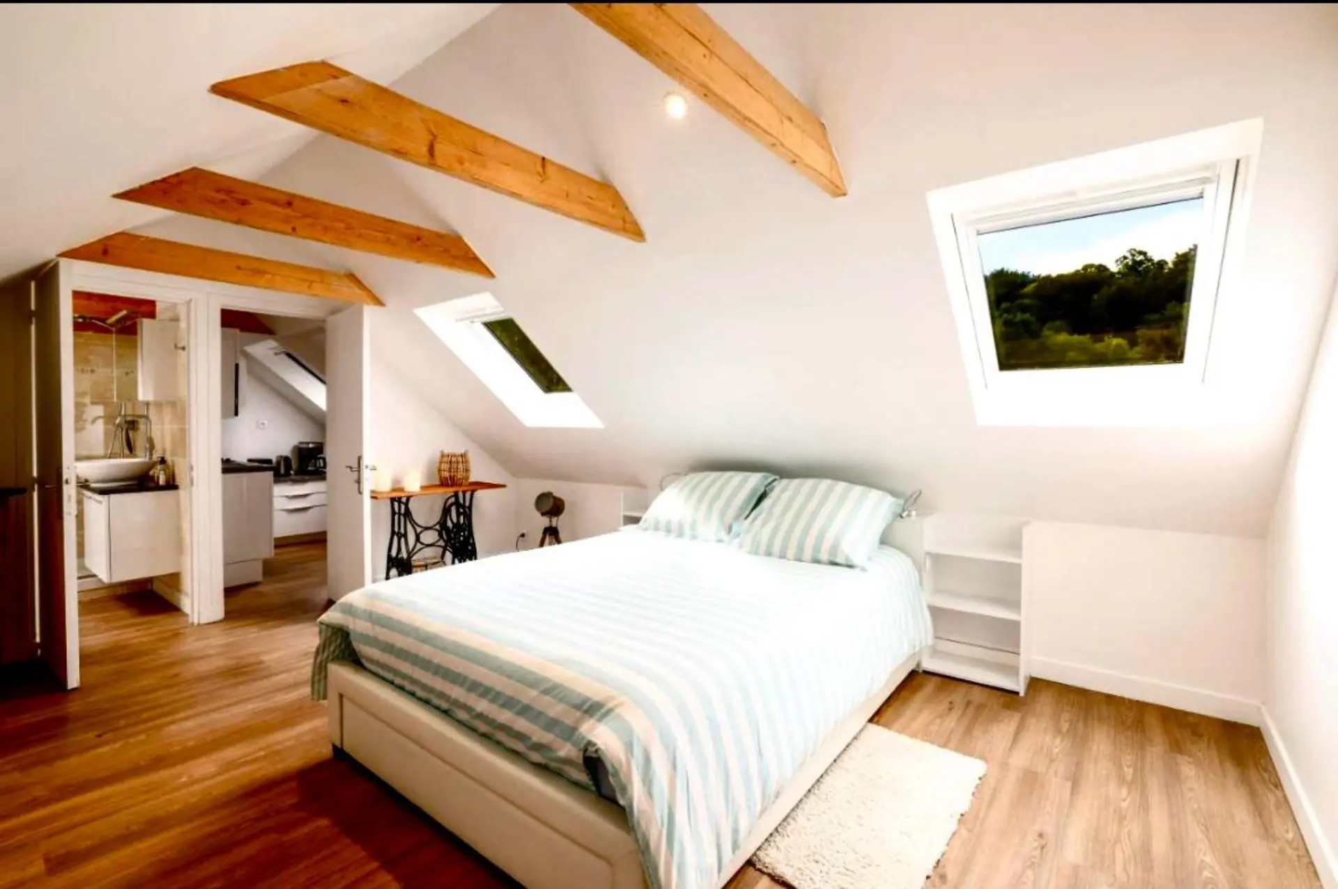 Chambre mansardée avec poutres et vue sur la nature