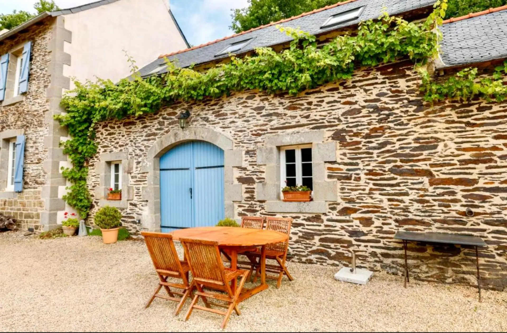 Façade du gîte de charme à Lopérec, Finistère, avec vigne grimpante et terrasse en pierre
