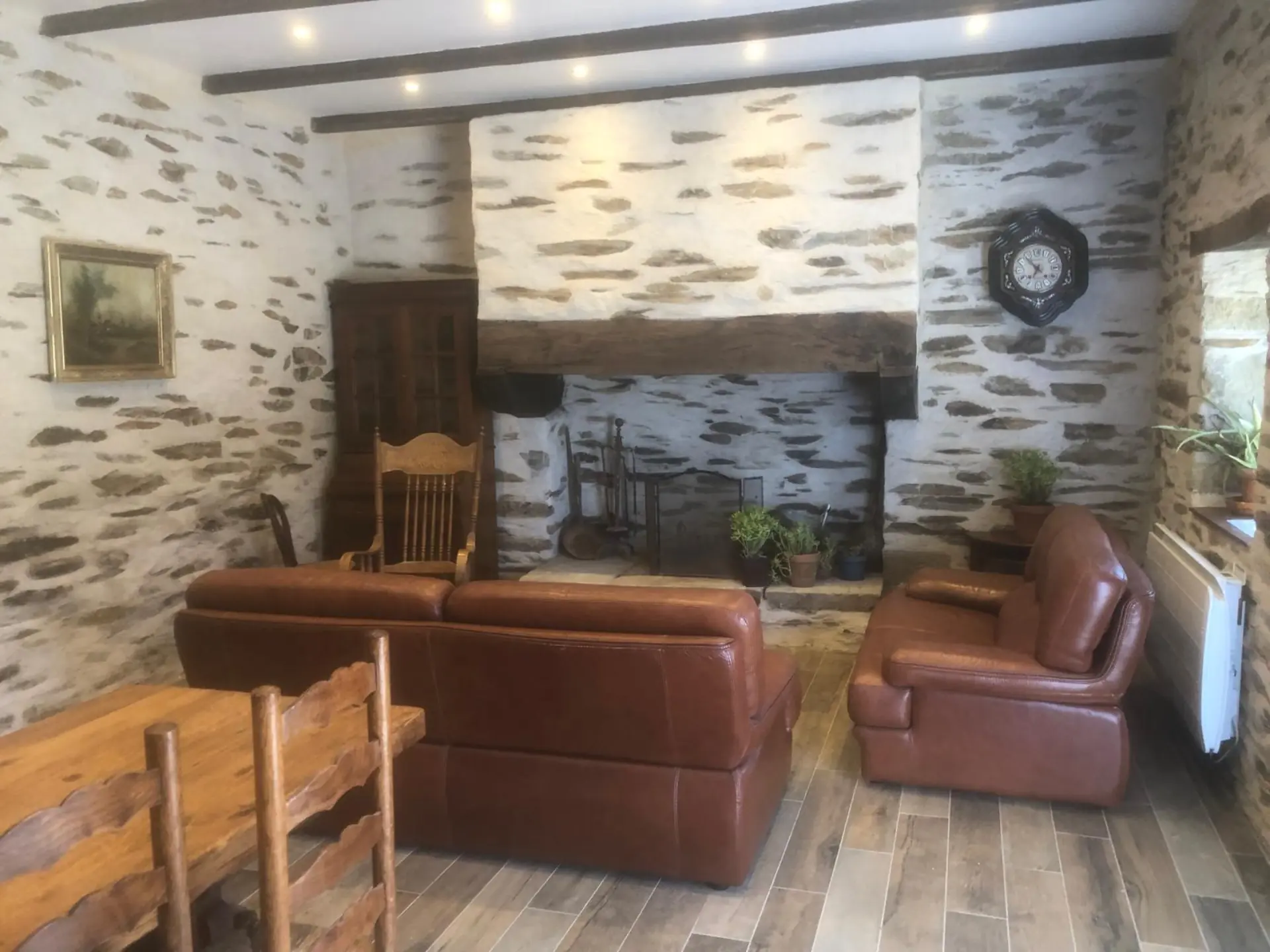 Coin cheminée avec fauteuils en cuir et poutres apparentes du gîte de charme à Lopérec, Bretagne