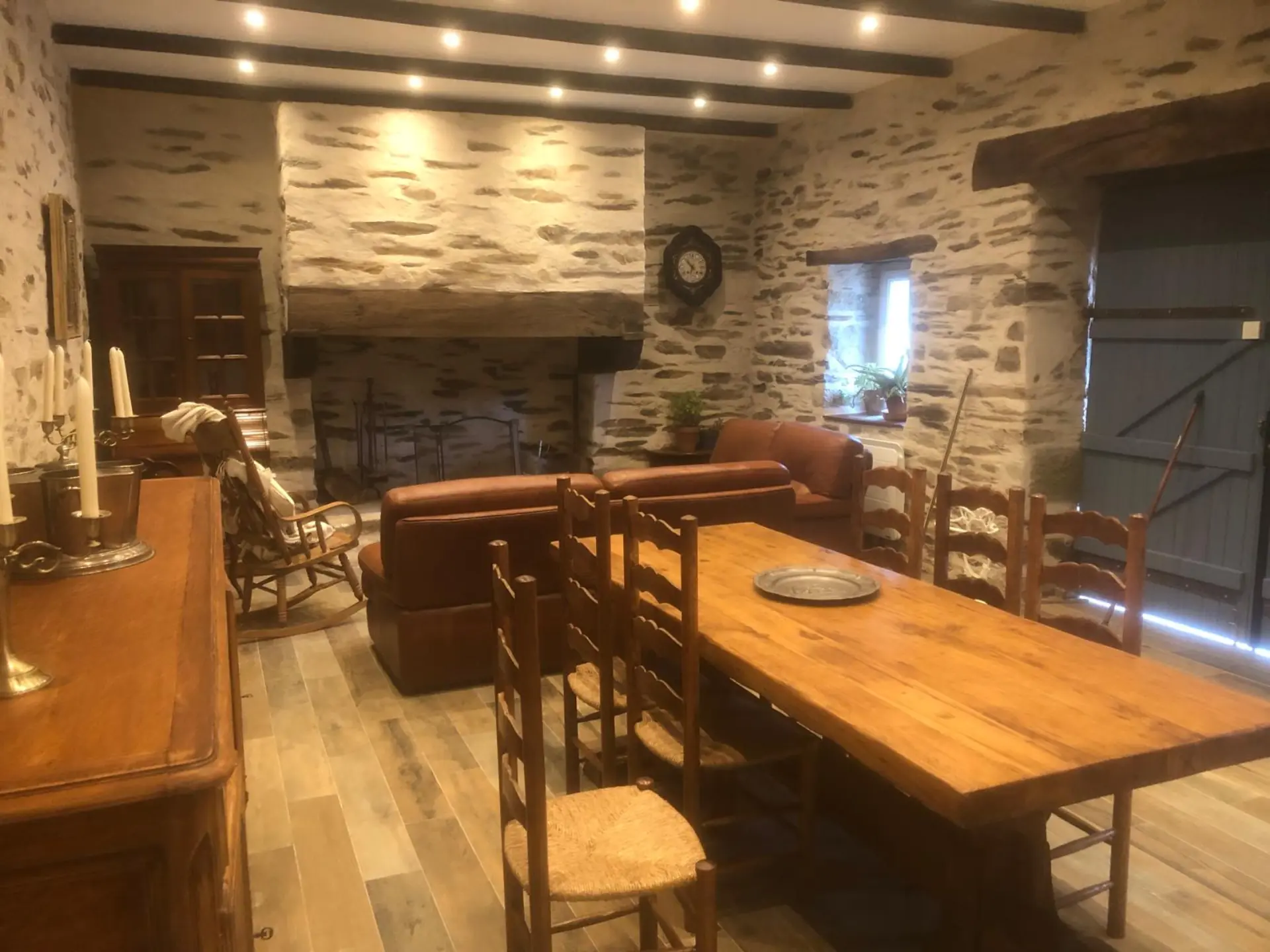 Salon avec cheminée en pierre et poutres apparentes