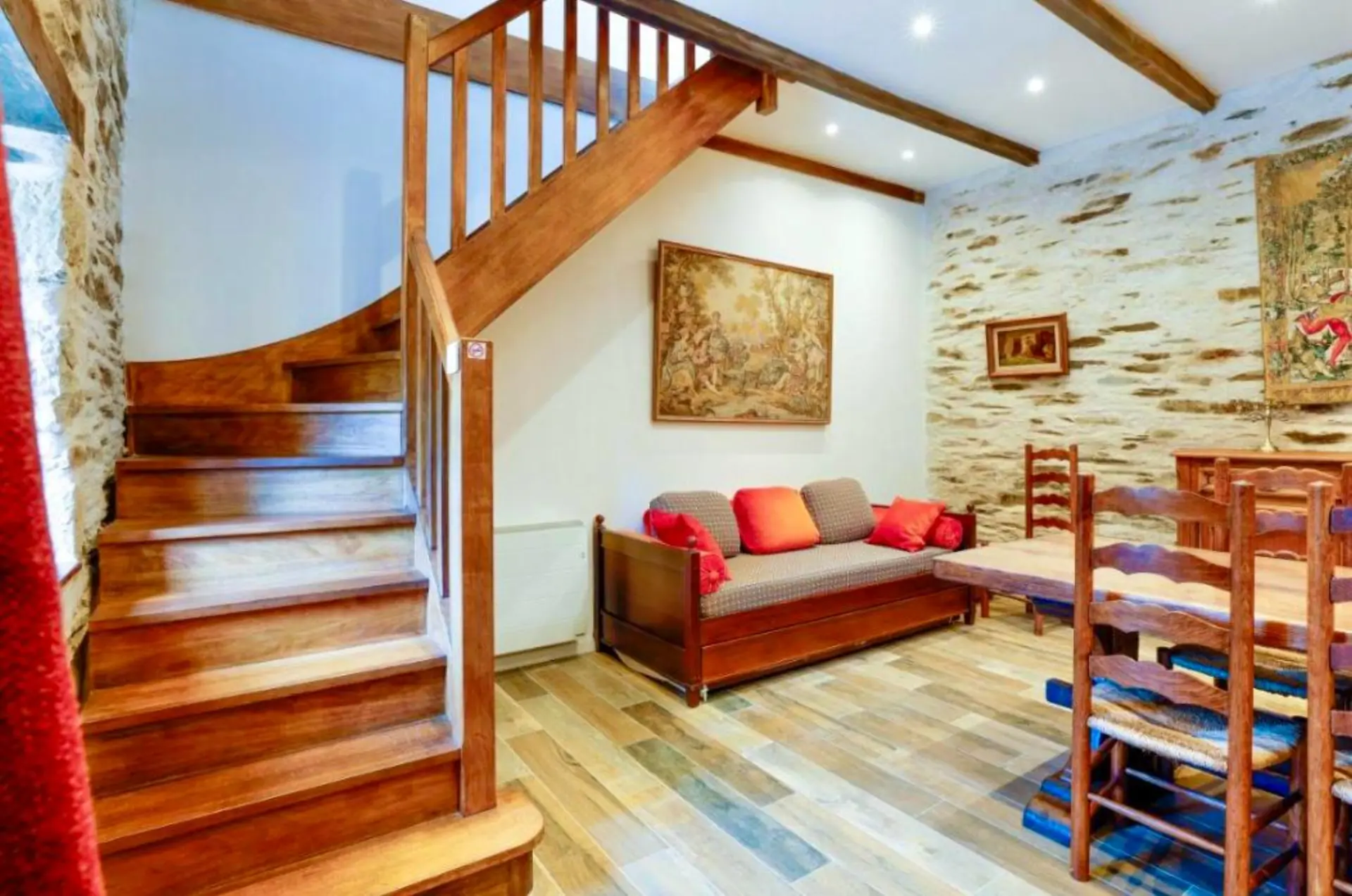 Séjour avec escalier en bois et murs en pierre