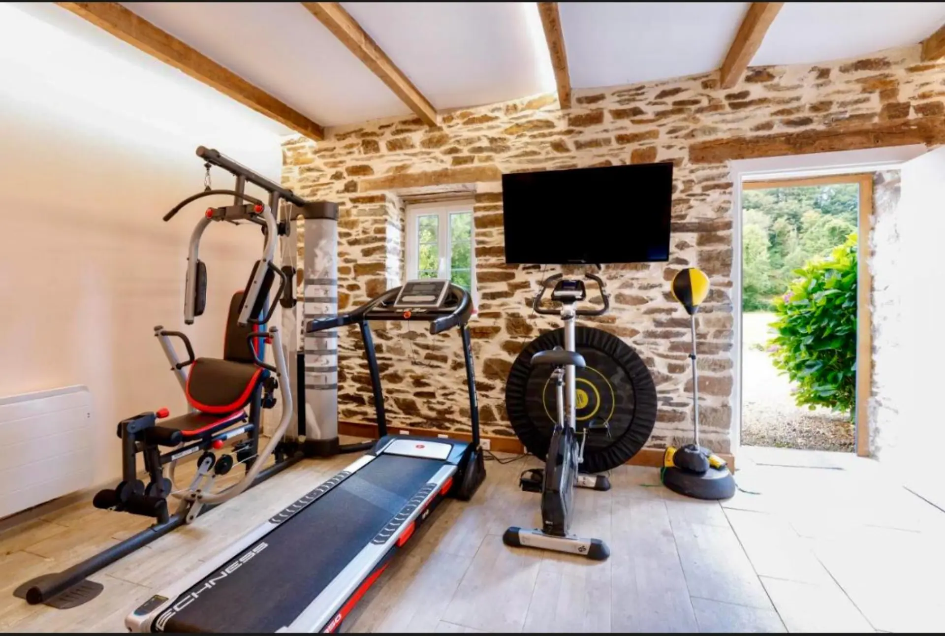 Salle de fitness complète avec murs en pierre